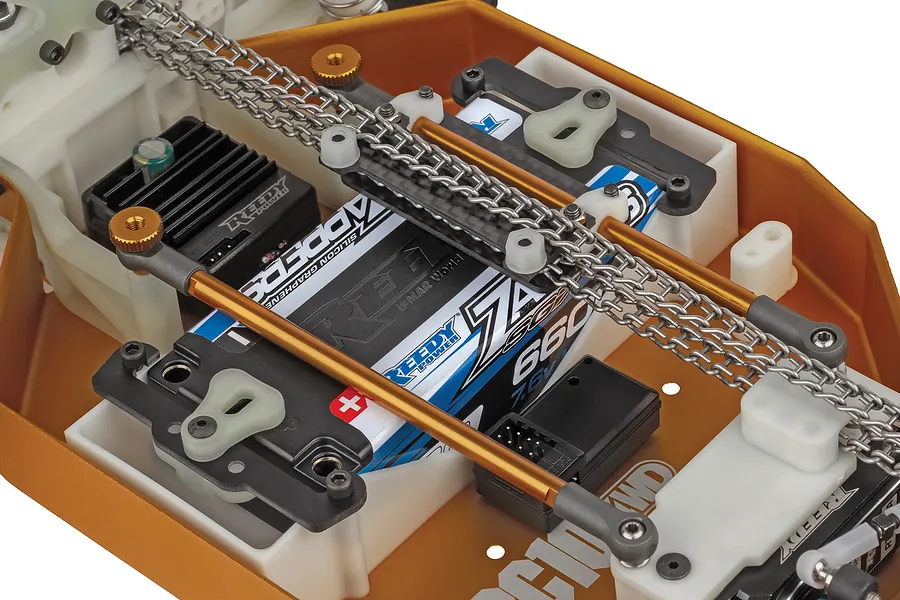 Close-up of the internal chassis of the Team Associated RC10 4WD buggy showing metal drive chains, battery, and electronics.