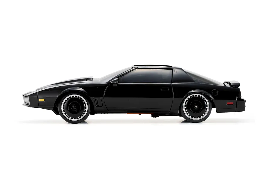 Studio side profile of the black Kyosho Mini-Z Knight Rider RC car showing detailed wheels and body against a plain white background.