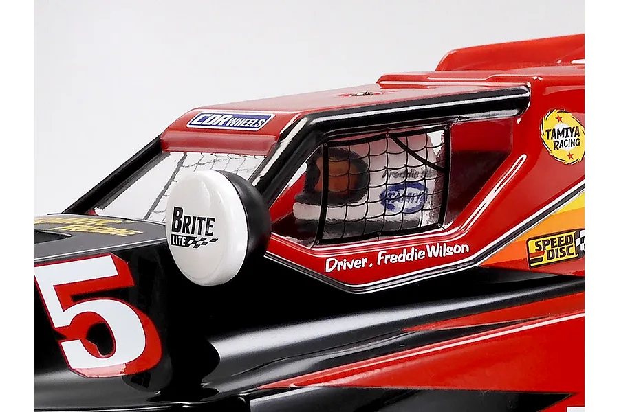 Close-up of the cockpit and driver figure on a red and black Tamiya RC buggy body with decals.
