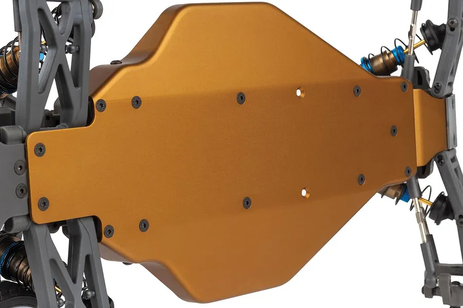 Close-up bottom view of the gold anodized aluminum chassis plate on an RC buggy, showing screws and suspension parts.
