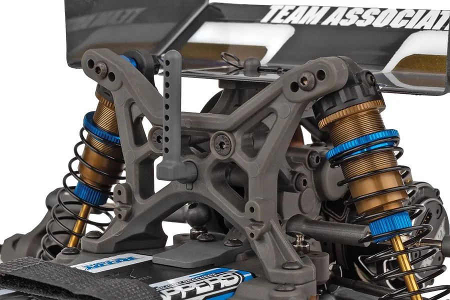 Close-up view of the rear suspension, shock towers, and shock absorbers on a Team Associated 1/10 scale RC buggy.