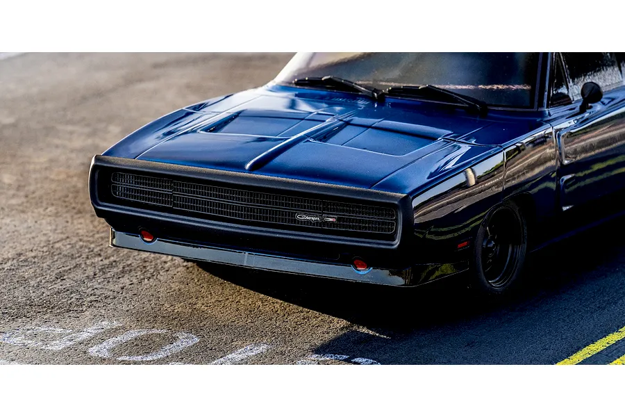 Close-up lifestyle shot of the front grille and hood of the blue Kyosho 1970 Dodge Charger RC car parked on asphalt.