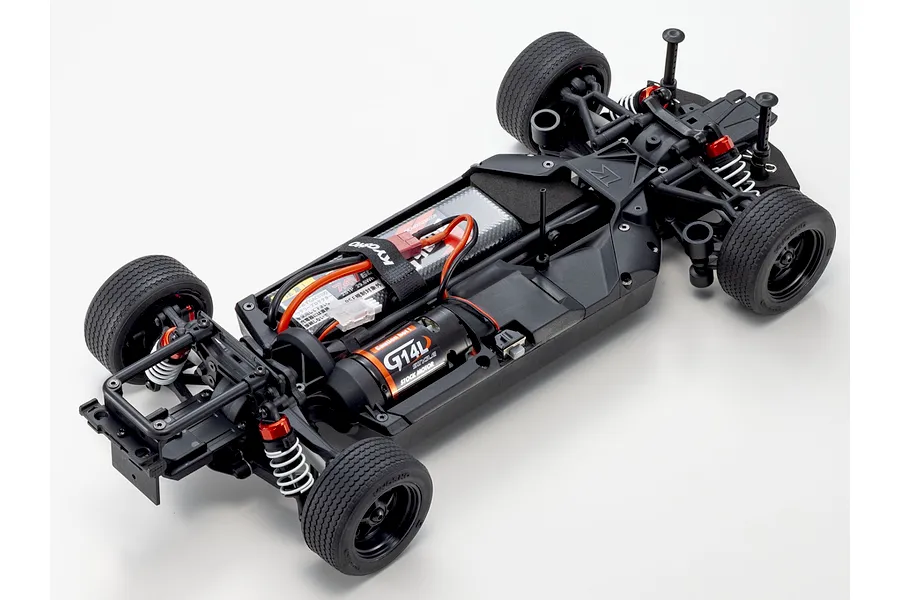 Top-down studio shot of the unpainted chassis of the Kyosho Fazer MK2 FZ02L RC car, showing electronics, motor, and suspension against a white background.