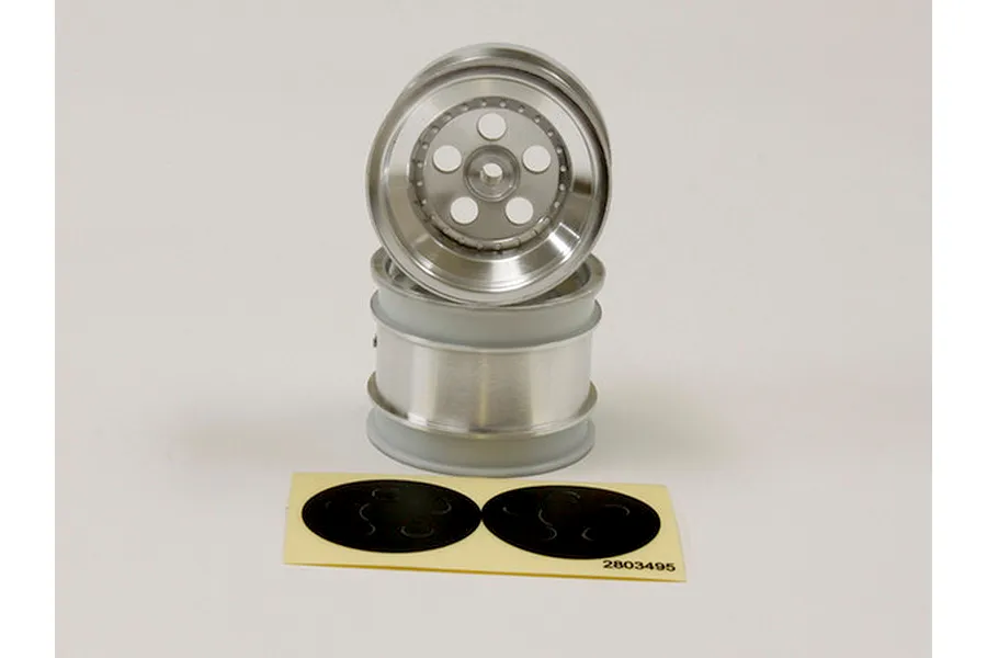 Two satin chrome RC buggy rims stacked vertically with a sheet of black circular stickers in front on a plain background.