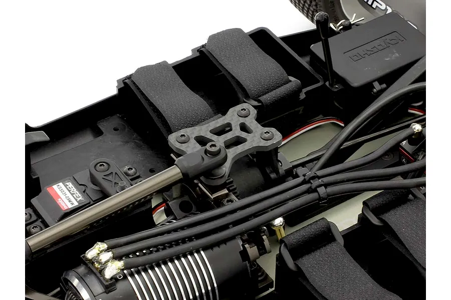 Close-up of a Kyosho RC car chassis interior featuring a carbon fibre top plate installed over the centre diff mount.