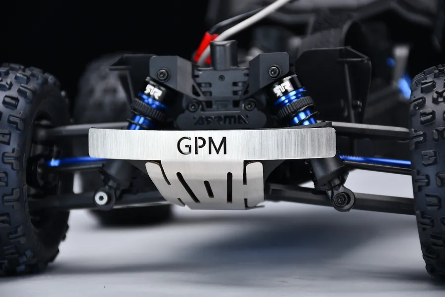 Close-up front view of an RC car chassis installed with a GPM silver stainless steel front skid plate featuring the GPM logo.