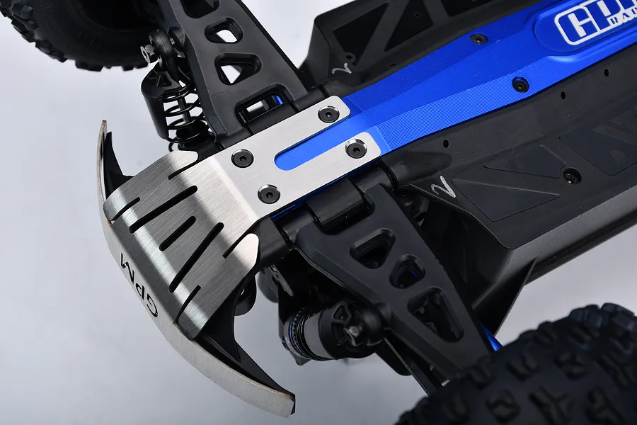 Close-up view of a silver stainless steel front skid plate installed on the front of an RC car chassis.