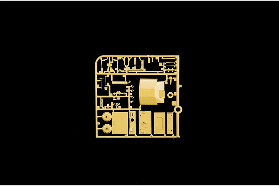 Tan plastic model kit sprue containing various parts and panels for military vehicle assembly against a black background.