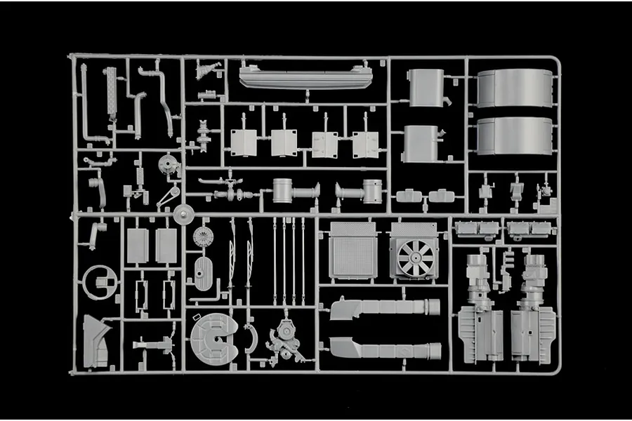 Grey plastic model kit parts sprue featuring truck parts like engine components, tanks, and structural elements on a black background.