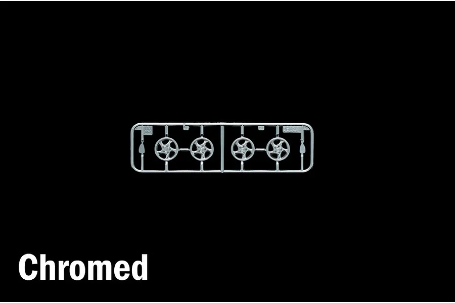 Chrome plated plastic model kit parts sprue containing four wheel rims against a black background with the word Chromed visible in the corner.