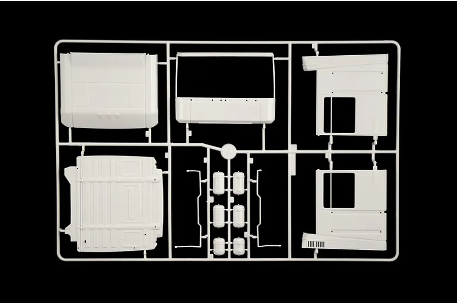 White plastic model kit sprue featuring truck cab panels and small accessory parts on a black background.