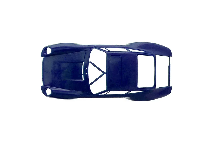 Top-down studio view of an unpainted dark blue plastic model car body shell against a white background.