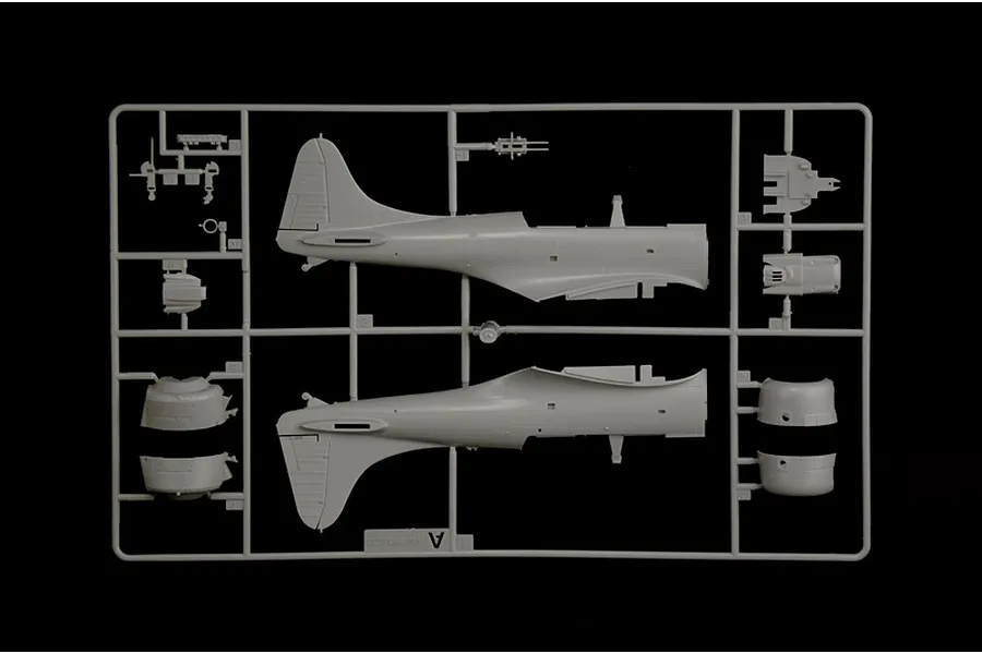 Grey plastic model kit sprue containing aircraft fuselage halves and small interior parts for the SBD-3 Dauntless bomber.