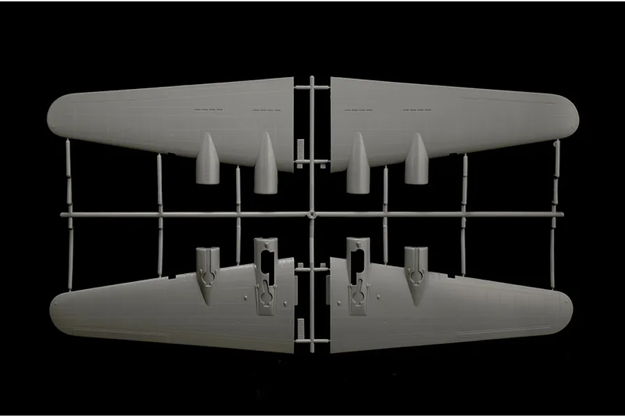 A grey plastic model airplane wing components still attached to their assembly sprue against a black background.