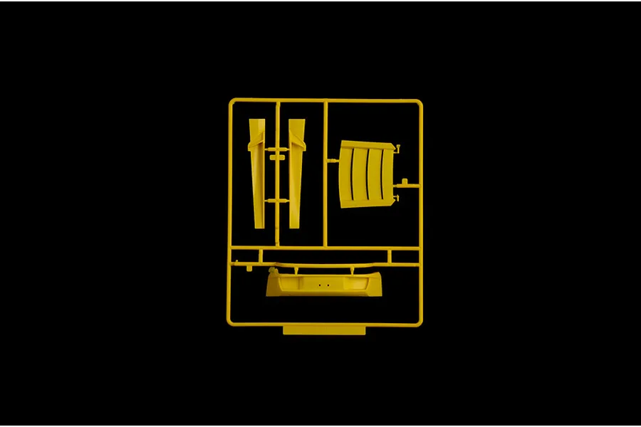 Yellow plastic model kit sprue containing car parts against a solid black background.