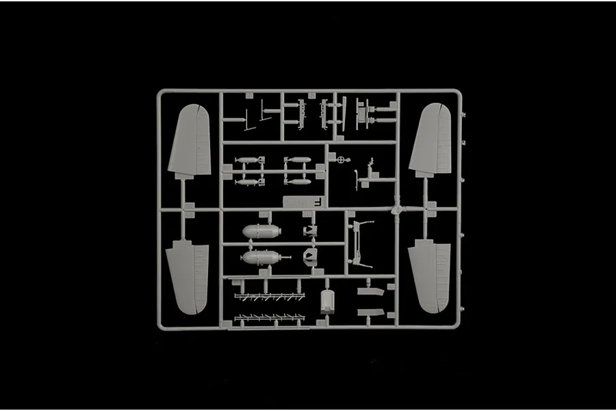 Grey plastic model kit sprue containing aircraft parts, wing sections, and ordnance components on a black background.