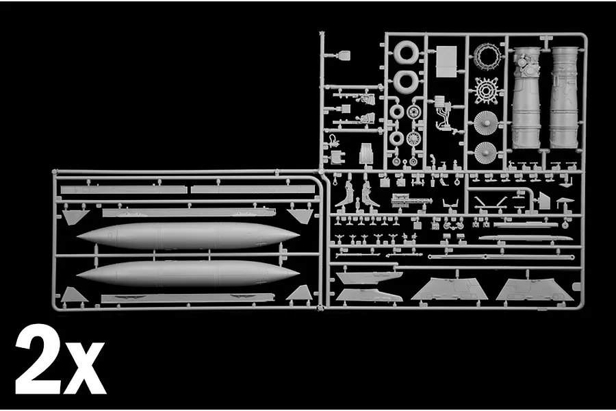 Grey plastic model kit sprues showing parts for an aircraft including fuel tanks, landing gear, and engine components labeled as 2x.