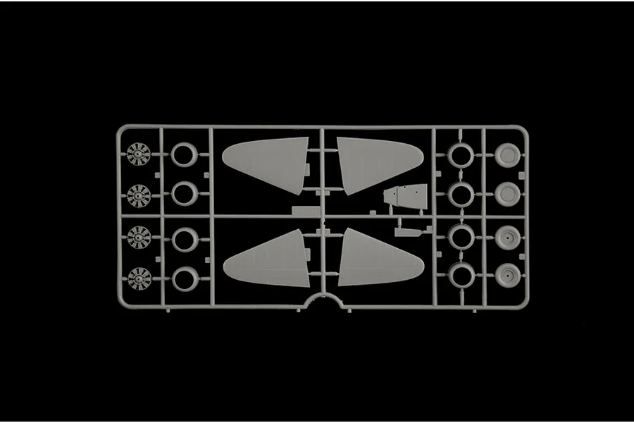 Grey plastic model sprue featuring aircraft parts such as engine cowlings, wheels, and control surfaces against a black background.