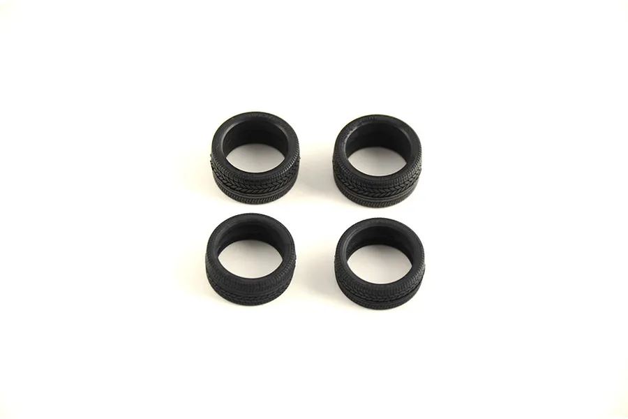 Four black rubber model car tires arranged in a square on a plain white background.