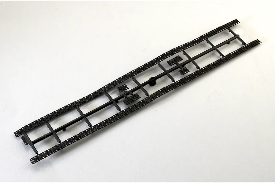 Black plastic model tank tracks sprue on a clean white background.