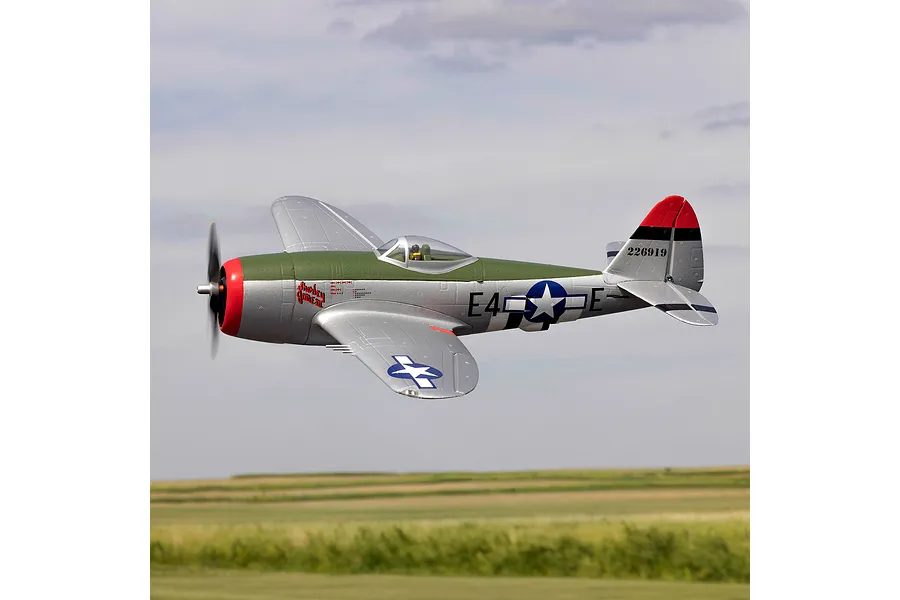 E-Flite Micro P-47 Thunderbolt RC warbird plane in flight against an outdoor field and cloudy sky background.