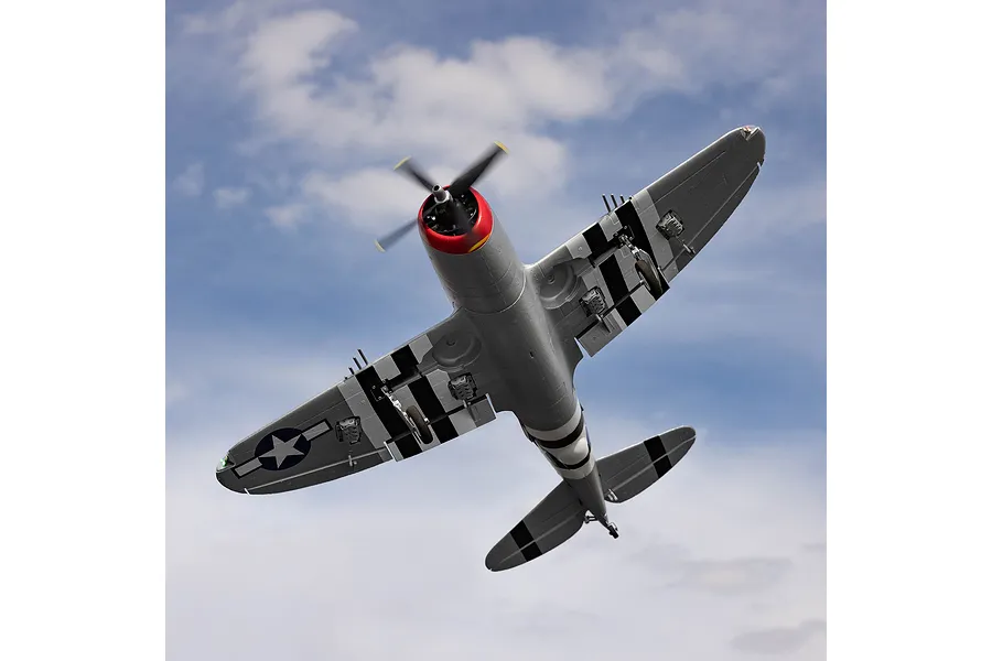 Underside view of the E-Flite Micro P-47 Thunderbolt RC warbird in flight against a cloudy blue sky.