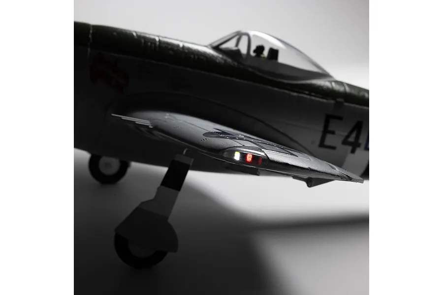 Close-up view of the E-Flite Micro P-47 Thunderbolt RC airplane showing illuminated wing tip lights and landing gear.