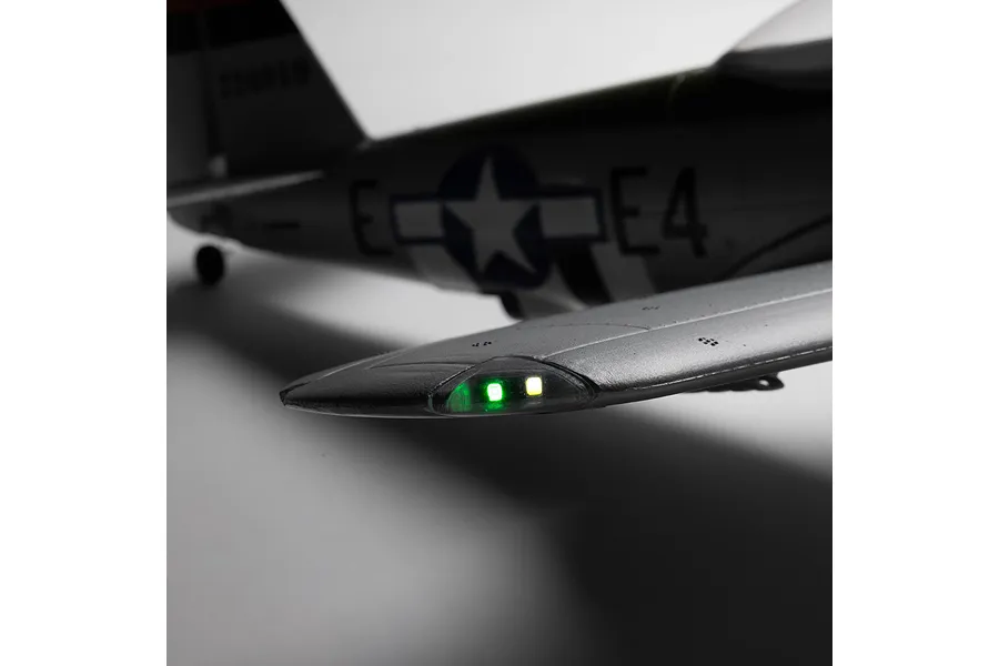 Close-up of the wingtip and navigation lights illuminated on the E-Flite Micro P-47 Thunderbolt RC airplane against a neutral background.