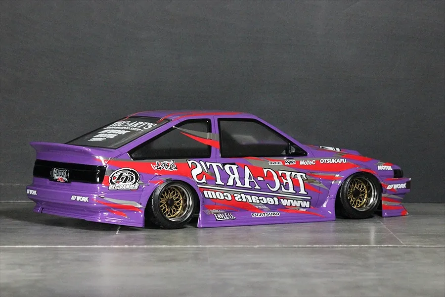 Purple RC drift car body featuring Tec-Arts decals, custom sponsor stickers, and gold mesh wheels viewed from the side and rear.