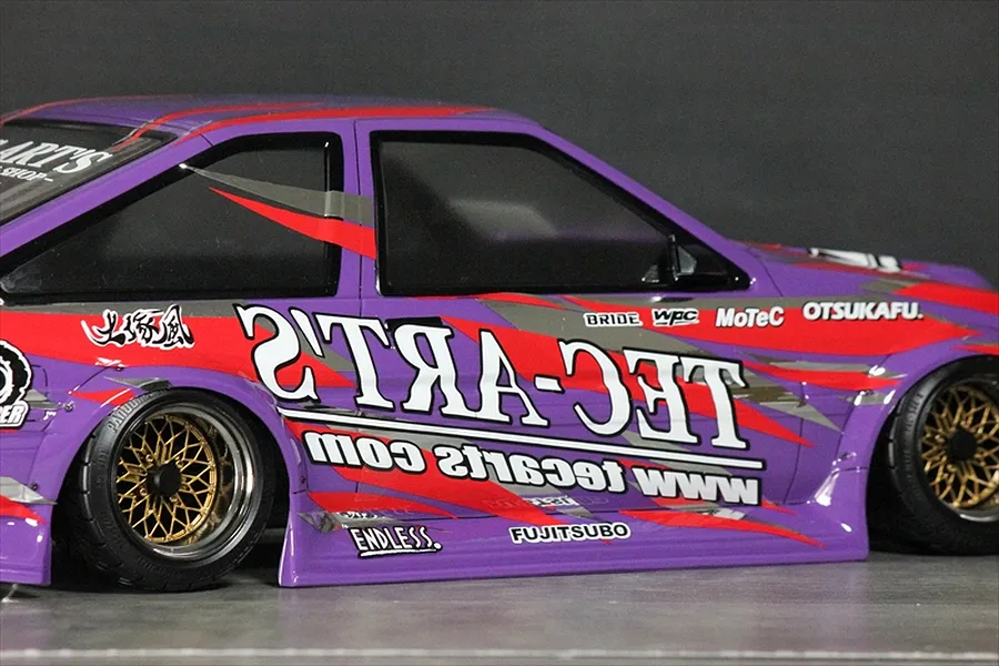 Side view of a purple RC drift car body featuring Ted Arts sponsor decals and gold mesh wheels.
