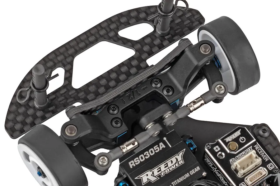 Close-up studio view of the front suspension, carbon fiber shock tower, steering servo, and electronics of the Team Associated RC285R.1 RC car.