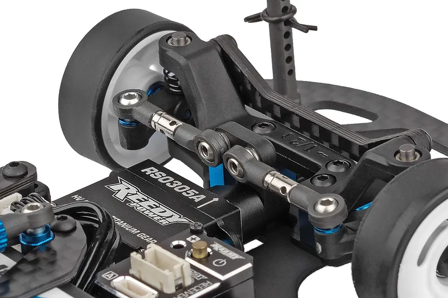 Close-up studio shot of the front suspension, steering servo, and carbon fiber chassis deck on a 1/28 scale RC car kit.