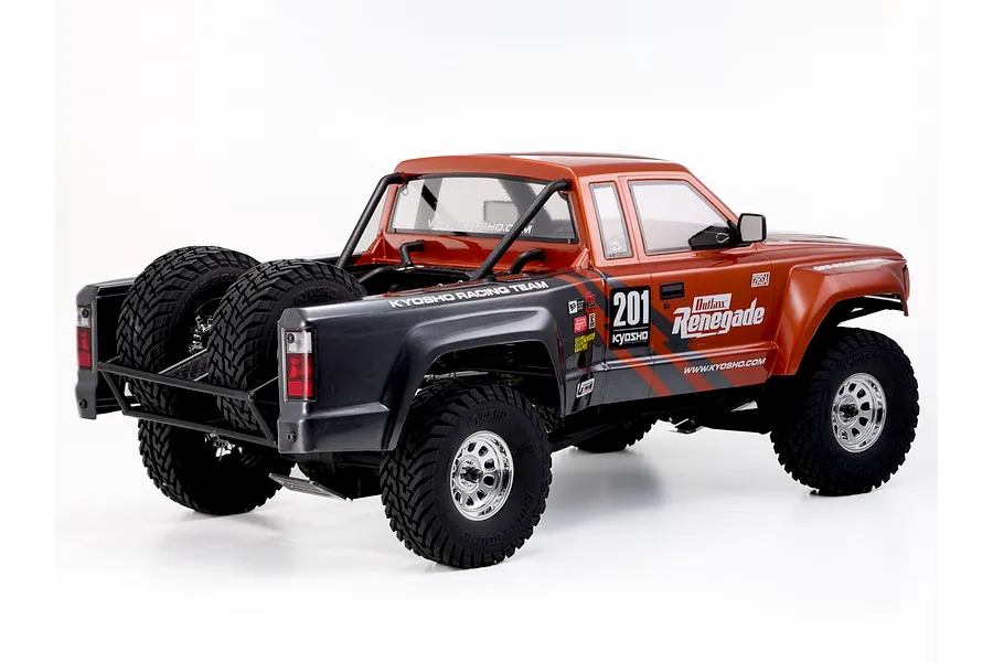 Rear-three-quarter studio shot of the Kyosho Outlaw Renegade 2RSA RC short course truck showing its orange and black livery and spare tires.