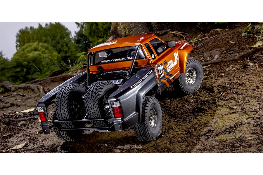Kyosho Outlaw Renegade 2RSA RC short course truck driving outdoors on a dirt track.