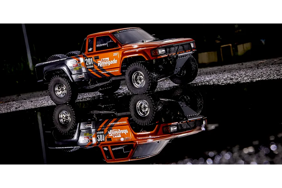 Kyosho Outlaw Renegade 2RSA RC short course truck parked by a puddle reflecting the vehicle in the dark.