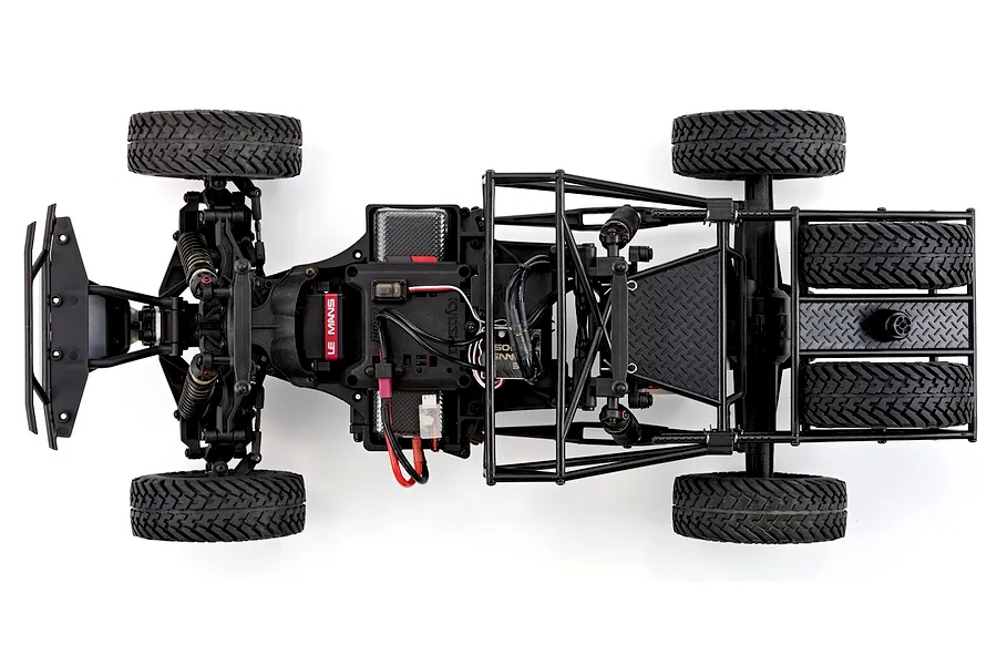 Top-down studio view of the RC car chassis showing internal electronics, suspension, and tires on a white background.