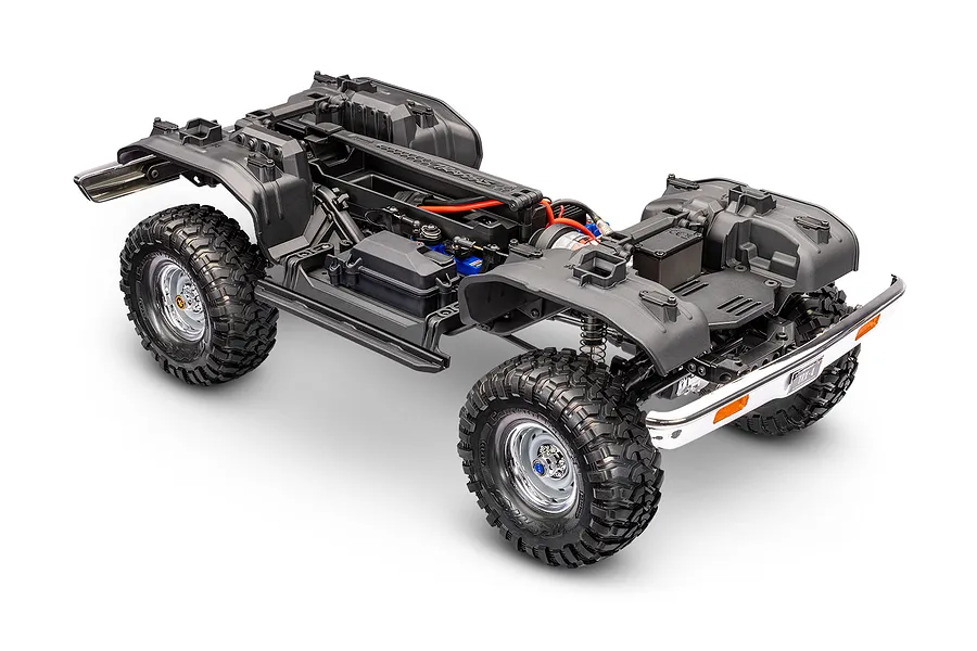 Traxxas TRX-4 RC crawler chassis without body, showing inner fenders, tires, and frame on a white background.