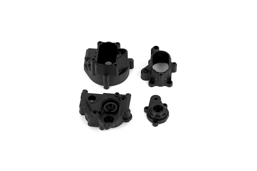 Four black plastic transmission housing and gearbox case parts for an RC car on a white background.