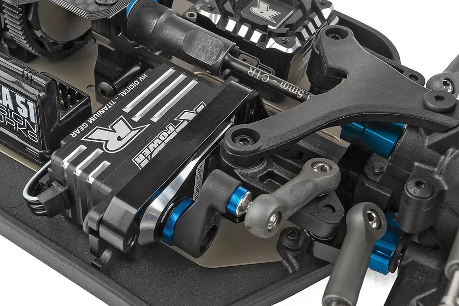 Close-up studio view of the steering servo, linkage, and chassis components inside the Team Associated RC buggy.