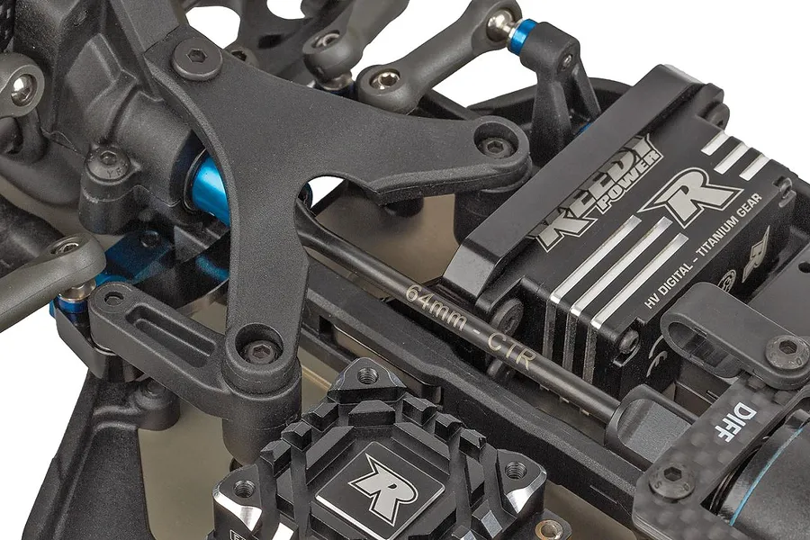Close-up of the steering mechanism and chassis components of a Team Associated RC car, showing linkage, servo, and mounting hardware.