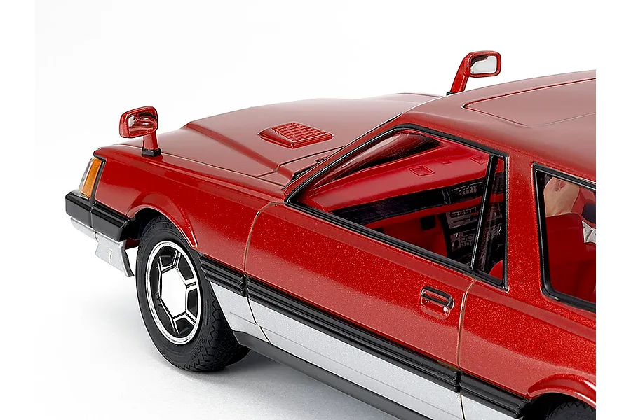 Close-up of the front quarter and interior of a painted red scale model car against a plain white background.