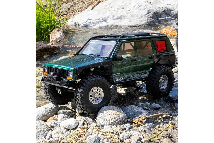 Axial SCX10 III Jeep Cherokee XJ RC rock crawler driving outdoors over rocks and through water.