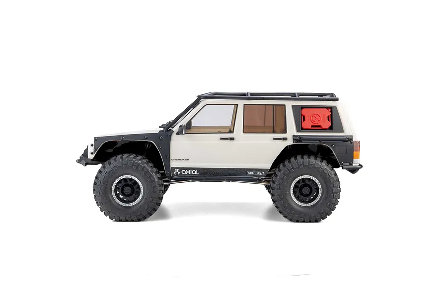 Studio side profile shot of the Axial SCX10 III Jeep Cherokee XJ RC rock crawler in white with black fenders and roof rack.