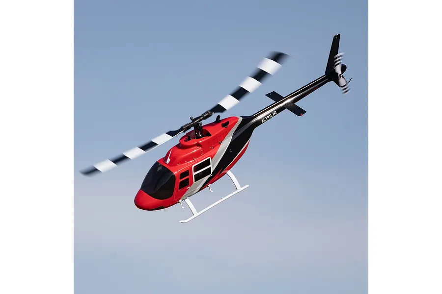 Red, white, and black Blade Jet Ranger RC helicopter in flight against a clear blue sky background.