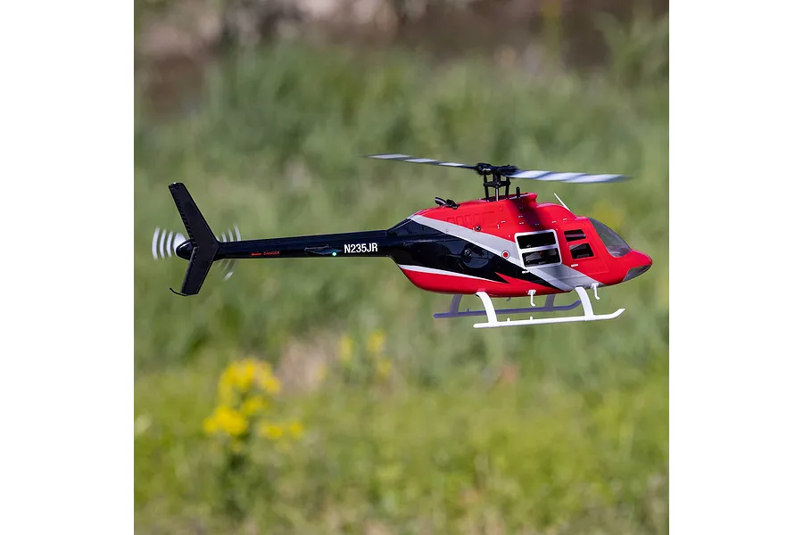 Blade Jet Ranger 235CP RC helicopter in flight outdoors against a green grassy background.