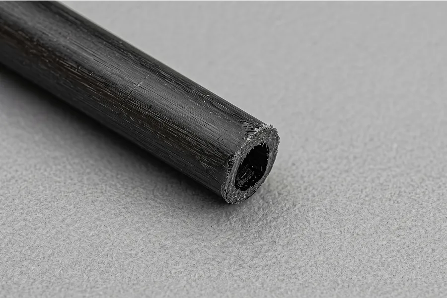 Close-up view of the textured end and surface of a Galaxy Carbon fibre tube against a grey background.