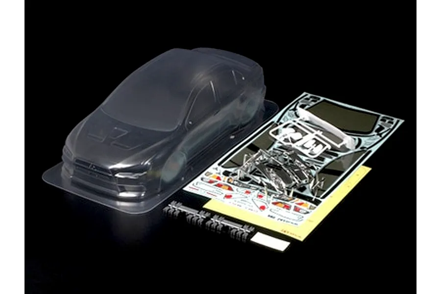 Tamiya 1/10 Mitsubishi Lancer Evolution X clear unpainted RC body shell with decals, masking sheets, and plastic accessories.
