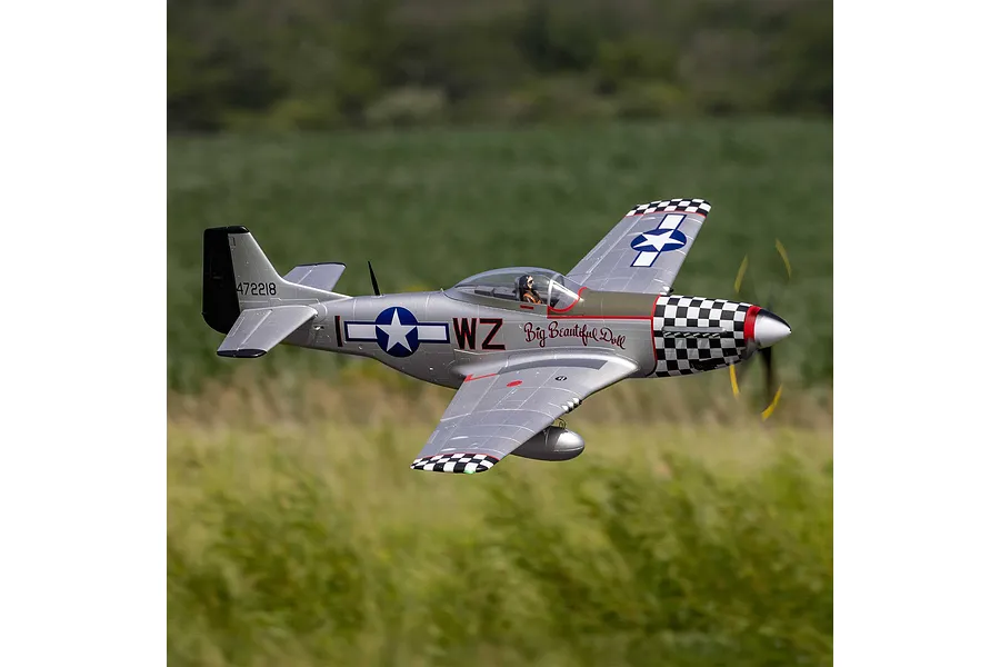 E-Flite P-51D Mustang Big Beautiful Doll RC fighter plane flying outdoors above a grassy field.
