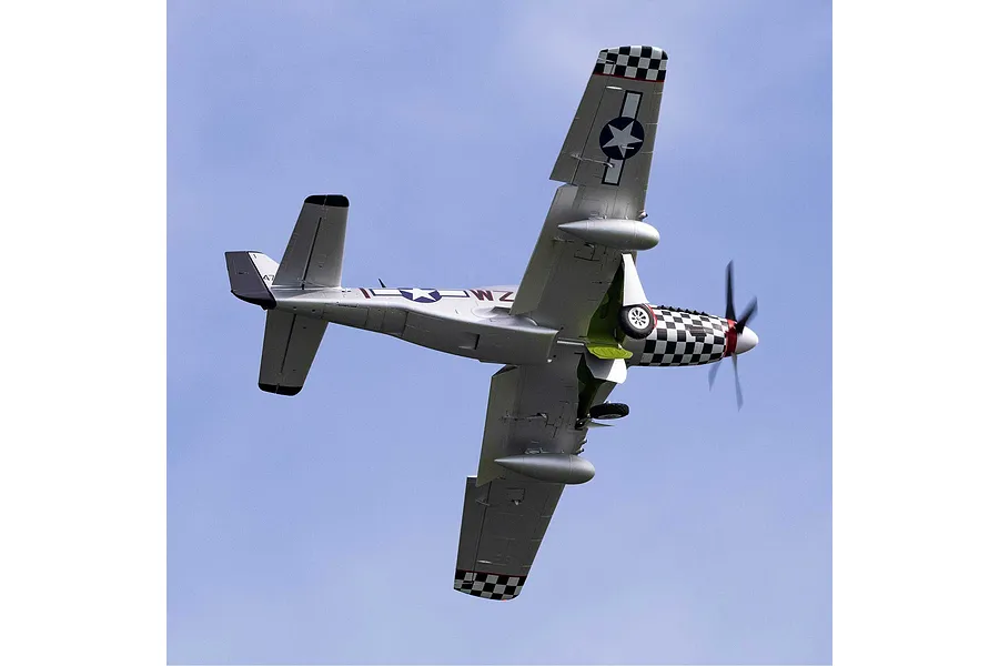 Underside view of the E-Flite P-51D Mustang Big Beautiful Doll RC airplane in flight against a clear blue sky background.