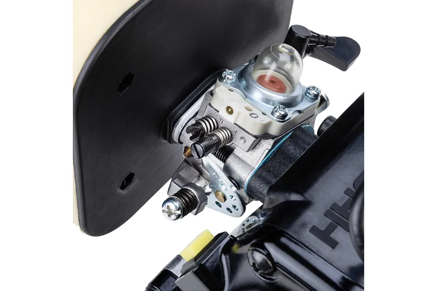 Close-up studio view of a petrol engine carburetor with primer bulb, air filter housing, and adjustment screws.